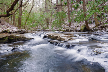 Obraz premium A clear mountain stream and water fall in winter with snow and ice. The Fiery Gizzard Trail on the Cumberland Plateau in Tracy City Tennessee USA.