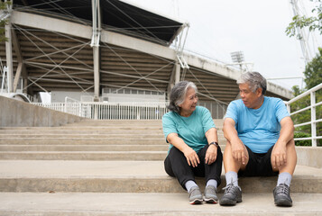 Happy and smile couples elderly asian sitting on stairs for rest after workout, jogging on morning, senior exercise outdoor for good healthy. Concept of healthcare and active lifestyle for healthy
