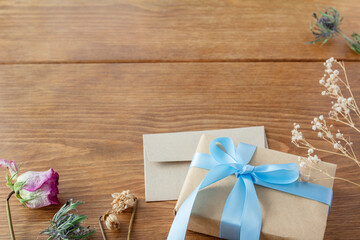 Decorative frame with light blue ribboned presents and dried flowers on a wooden table