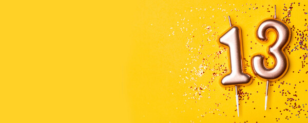 Gold candles in the form of number thirteen on yellow background with confetti. 13 years celebration. - obrazy, fototapety, plakaty