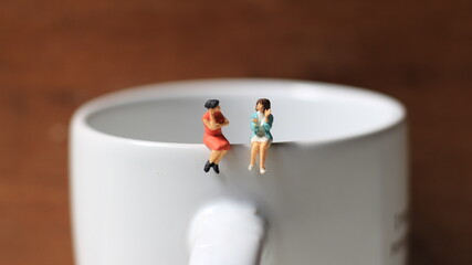Miniature figures of 2 women talking over glasses. discussion concept.