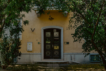 the doorway of an apartment building next to green vegetation in a shady place in budapest