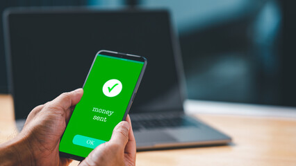 A businessman hand holds a smartphone on the screen with the message money sent transfer Concept. business, banking, financial online transactions with mobile devices. Copy space, Blurred background