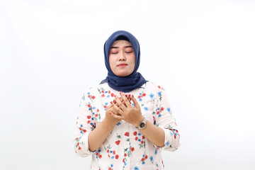 Asian veiled woman standing while praying. Isolated on white background