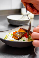 chef hand cooking grilled salmon fish fillet with creamy ptitim, cheese and caviar