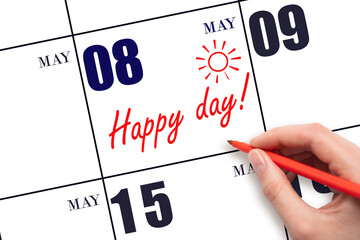 Hand writing the text HAPPY DAY and drawing the sun on the calendar date May 8