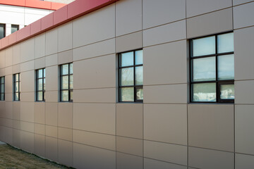 The exterior wall of a contemporary commercial style building with aluminum metal composite panels and glass windows. The futuristic building has engineered diagonal cladding steel frame panels.  