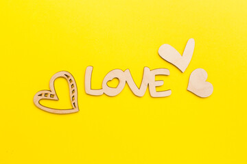 Wooden word love with hearts on color background, top view