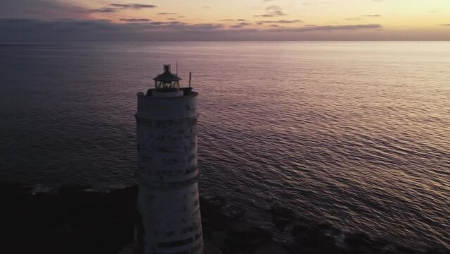 Closeup aerial of Calasetta Lighthouse, known as Mangia Barche, circle pan, dusk
