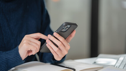 Close-up hand of a businesswoman using a smartphone at her office.