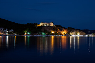 Fototapeta na wymiar Old buildings lit at night across the Water in Thassos.