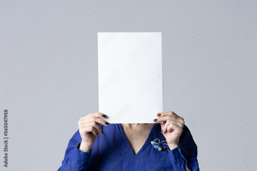 Wall mural Woman covering her face with a white poster