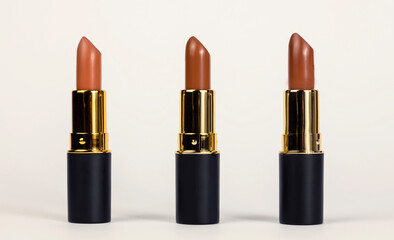 Fototapeta na wymiar Lipsticks for lips. Three brown lipsticks of different shades on a white background. Beauty concept.