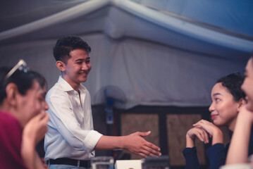 A handsome young man initiates a handshake as he confidently introduces himself to a beautiful...