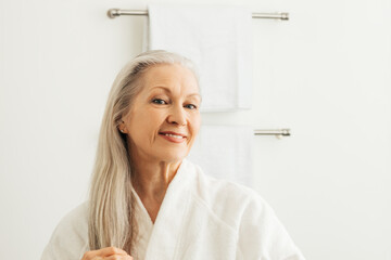 Smiling senior woman with long gray hair looking at her reflection - Powered by Adobe