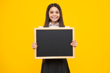 Fototapeta premium Teenager child holding blank chalkboard for message Isolated on a yellow background. Empty text blackboard, copy space mock up. Happy girl face, positive and smiling emotions.