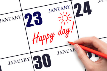 Hand writing the text HAPPY DAY and drawing the sun on the calendar date January 23