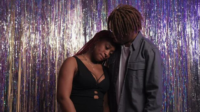 Couple support. Depressed feelings. Boring party. Sad black woman leaning head on beloved man shoulder posing silver cascade curtain background.