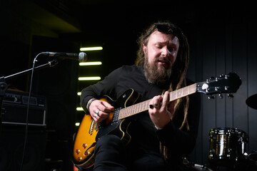 Obraz premium Guitarist man plays an electric guitar Close-up at studio