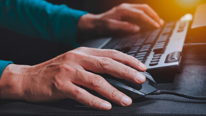 Closeup a guy using computer with hand on mouse and keyboard. Office worker operate computer.