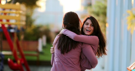 Two adult happy sisters posing together outside twin siblings with same clothes