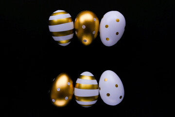 Gold Easter eggs in a row on a black background. Festive Easter concept. Flat style, space for text.