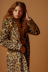 Fashionable confident redhead freckled lady wearing trendy faux fur coat with leopard print. Studio...