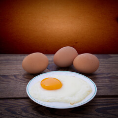 Plate with fried eggs on wooden background