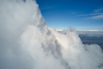 Aerial view from airplane window at high altitude of earth covered with white puffy cumulus clouds