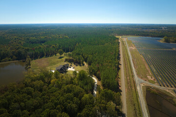 Aerial view of a house near big electric power plant with many rows of solar photovoltaic panels for producing clean electrical energy. Renewable electricity with zero emission concept