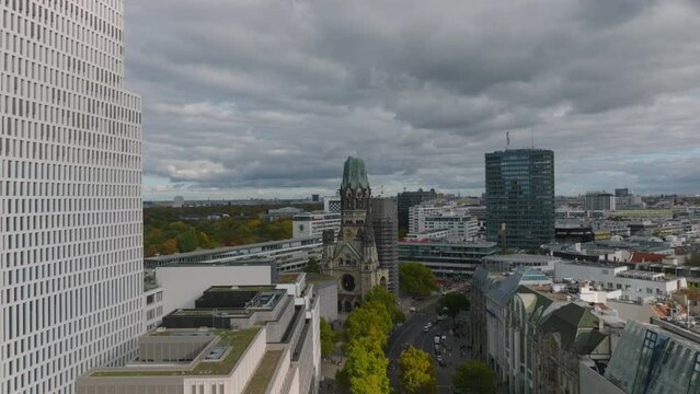 Fly above buildings in urban borough. Slide and pan shot of old church. Charlottenburg neighbourhood, Berlin, Germany