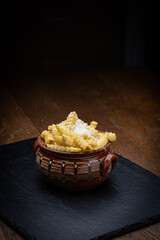 Bulgarian fries with feta is a popular snack or side dish often found in Bulgarian restaurants, cafes, and street food vendors. Served in a gyuveche clay pot placed on stone surface.