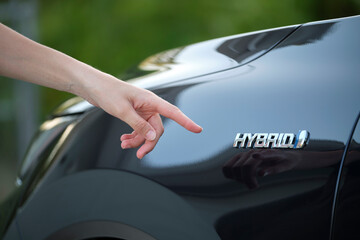 Human hand showing hybrid car sign on new effective vehicle
