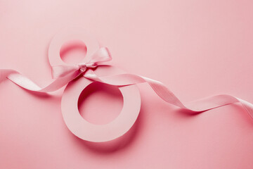 March 8. Paper cut number 8 on a pink background with a ribbon