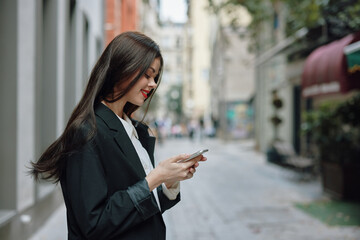 Business brunette woman with red lips smile with teeth with a phone in her hands, white shirt and black jacket fashion on the street, summer trip, vacation in the city tourist