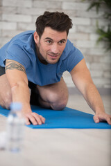 man stretching forwards on yoga mat
