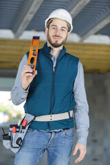 portrait of a male building contractor holding spirit level