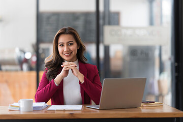 Attractive young asian woman using laptop computer while standing in a office.