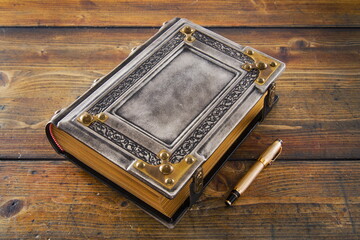 Vintage, medieval, aged white leather book with embossed frame and metal corners lay down to wooden...