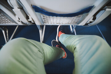 Personal perspective on legroom between seats in airplane. Man resting during flight. . - obrazy, fototapety, plakaty