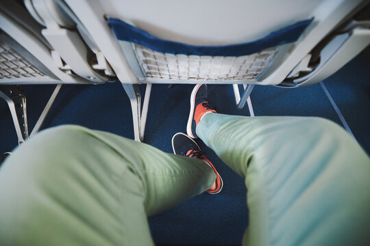 Personal perspective on legroom between seats in airplane. Man resting during flight. .