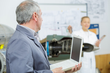 side view of mature male technician using laptop in workshop