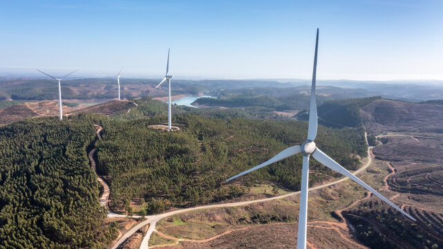 Wind turbines generate clean, green electricity in the fields of Portugal. With a view of the Bravura dam.