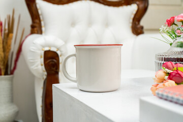A white blank enamel mug standing out on the corner of a white box with some snacks decorated around it