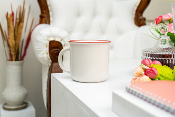 A white blank enamel mug standing out on the corner of a white box with some snacks decorated around it