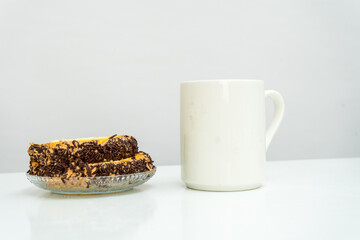 A white blank coffee mug standing out on the top of a white book with a snack placed near it