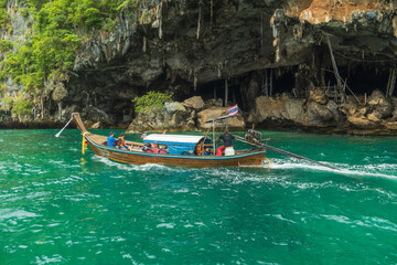 Naklejka na ściany i meble Krabi, Thailand - May 12 2022 : Long-tailed boats are taking tourists travel to see the view of Phi Phi Leh Island in Phi Phi Islands National Park.