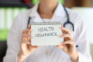 Female doctor shows notepad with words health insurance close up.