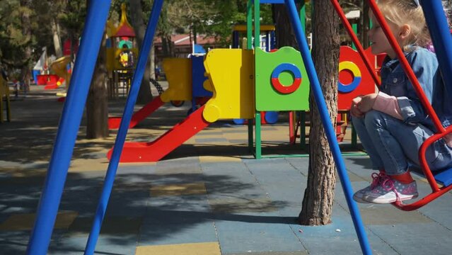 playgroung, childhood - little blonde girl at the playground on the swing