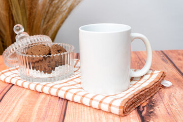 Fototapeta na wymiar A white blank coffee mug on the top of a hand cloth with some crackers arranged beside it